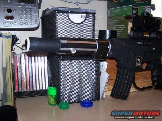 toy gun with scope and extended barrel, next to CDs and a phone