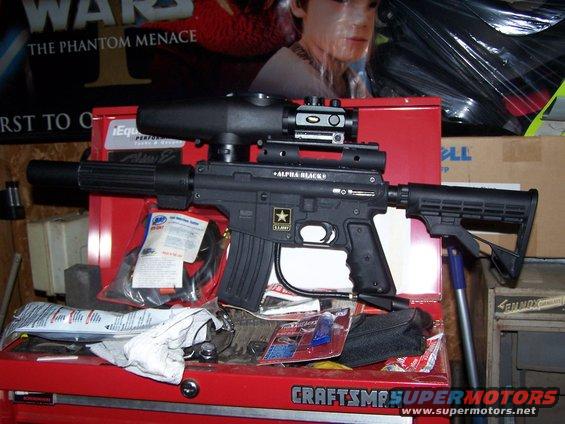 Black paintball gun with scope and "ALPHA BLACK" marking