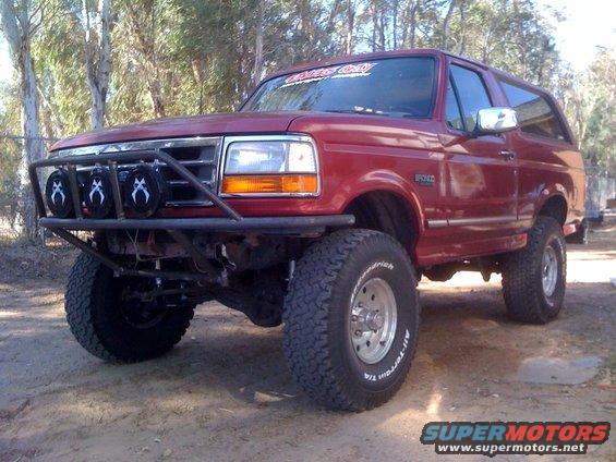 Red 1992 Ford Bronco with custom front bumper and off-road lights