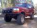 1989 Ford Bronco - This red Ford Bronco features a custom front bumper and auxiliary lights, suggesting off-road modifications.