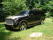 2000 Ford Excursion - This Ford Excursion is parked in a grassy, wooded area, showing its two-tone paint and custom wheels.