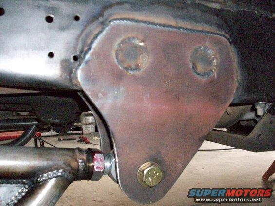 Close-up of a welded metal bracket on a vehicle frame with a large bolt