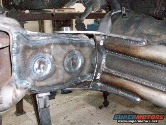 Welded frame section with circular cutouts and metal tubing, viewed from below
