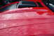 2004 Ford Mustang - A red car hood with black racing stripes and a hood scoop shows reflections of the sky and trees.