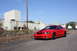 2004 Ford Mustang - A red 2004 Ford Mustang coupe is parked outside industrial buildings under a clear blue sky.