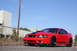 2004 Ford Mustang - A red 2004 Ford Mustang coupe is shown from a three-quarter front view, black racing stripes on the hood and sides.