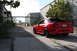 2004 Ford Mustang - A red 2004 Ford Mustang is parked in an alley between industrial buildings.
