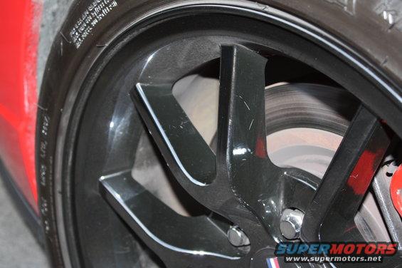 Red car fender and black alloy wheel with red brake caliper
