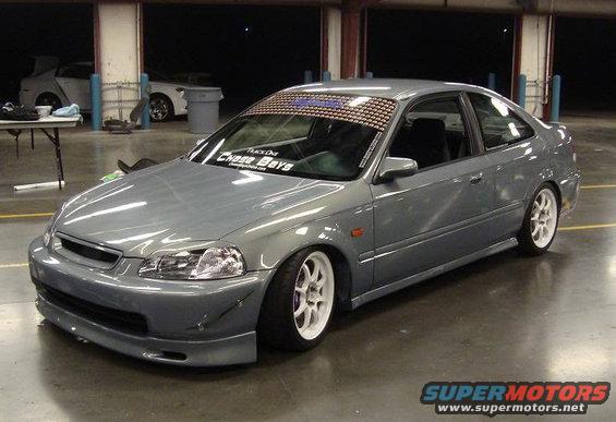 Gray 1999 Honda Civic coupe with white wheels and aftermarket body kit parked indoors. Another white car is visible in the background