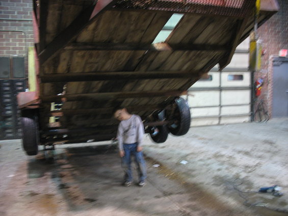 Person lying down under a trailer in a garage