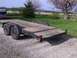 1900 Ford C-350 (Centurion Conversions) - A dual-axle car trailer with a weathered wooden deck sits on a gravel surface.