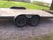 1900 Ford C-350 (Centurion Conversions) - A side view of a trailer with two axles and a wooden deck, parked on gravel.