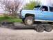 1900 Ford C-350 (Centurion Conversions) - A blue SUV is loaded onto a flatbed trailer, with a spare tire secured to the front of the trailer.