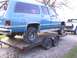 1900 Ford C-350 (Centurion Conversions) - Blue SUV being transported on a trailer, with a white pickup truck in the background.