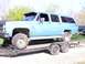 1900 Ford C-350 (Centurion Conversions) - An extended blue SUV is loaded onto a trailer, showing its lifted suspension and large off-road tires.