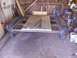 1900 Ford C-350 (Centurion Conversions) - A trailer frame with a wooden deck is shown in a workshop setting.