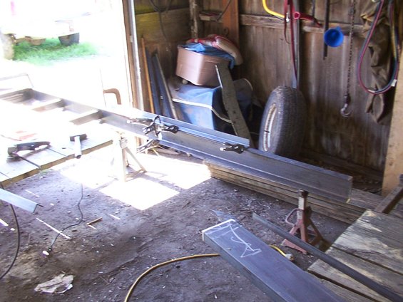 Metal beams clamped on sawhorses with a spare tire in the background