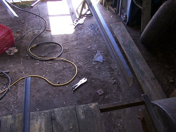 Workshop floor with coiled cables, pliers, metal beams, and wooden planks