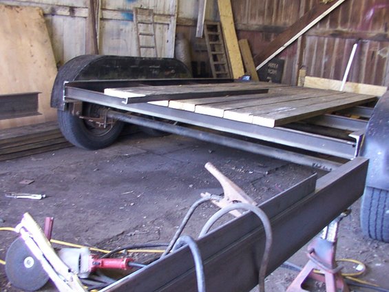 Trailer frame with wooden planks on top, in a workshop with tools