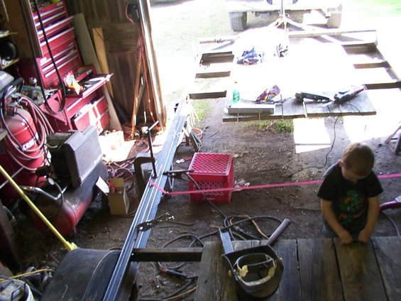 Garage interior with tools, air compressor, and a child sitting at a wooden surface