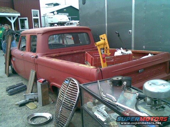 Red pickup truck with a custom grille and parts scattered around