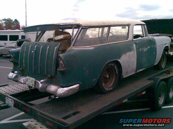 Station wagon on a trailer, rear view, green and primer body, chrome bumper, vertical taillights