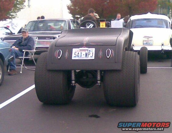 Hot rod with large rear tires and custom paint, license plate 541-WPJ. Other cars visible in background