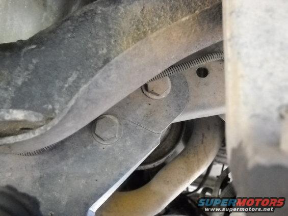 Close-up of a cracked metal bracket on a vehicle's suspension system