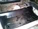 1969 Ford Mustang - The interior floor pan of a vehicle, showing a fresh black coating and pre-drilled holes for mounting components.