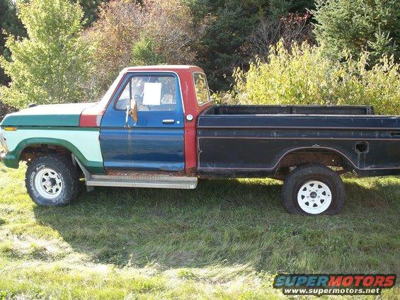 Ford pickup truck with mismatched paint panels, flat rear tire, and white wheels, seen from the side