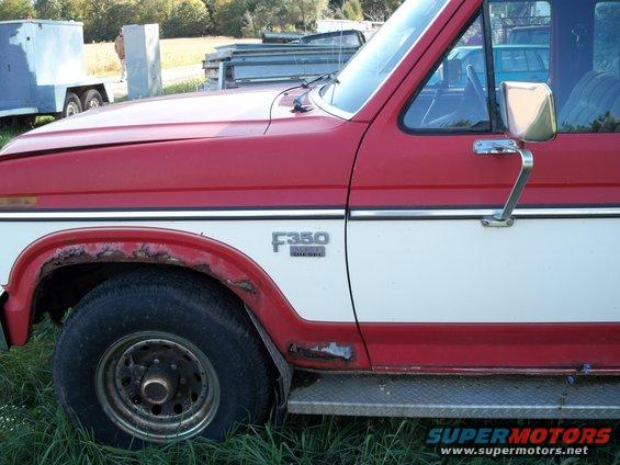 Side view of a red and white Ford F-350 Diesel truck with rust around the wheel well
