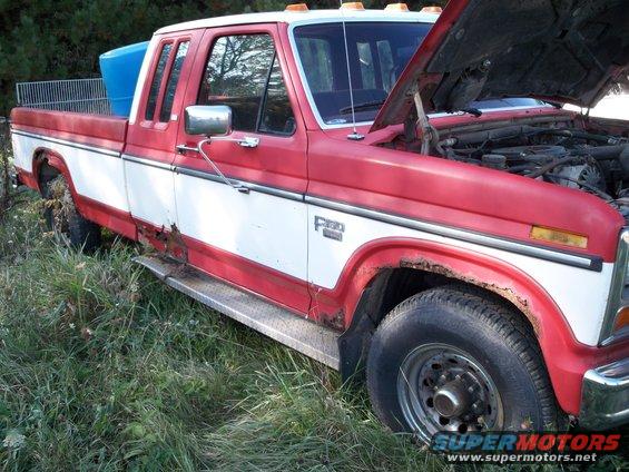 1987 Ford F-150 pickup truck, red and white, with hood open and rust on fenders