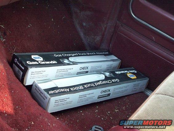 Two boxes of NAPA Gas Grande shock absorbers sitting on the floor of a vehicle's interior