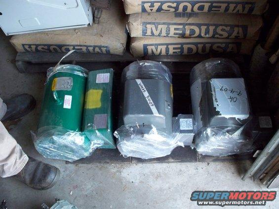 Three industrial electric motors wrapped in plastic, with bags of Medusa cement in the background