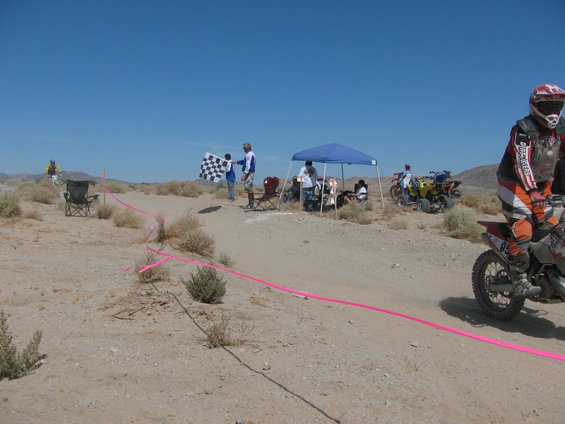Dirt bike race with checkered flag, tents, and ATVs in a desert landscape