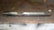 1997 Ford Ranger - A metal rod part with distinctive cutouts is shown against a wooden surface.