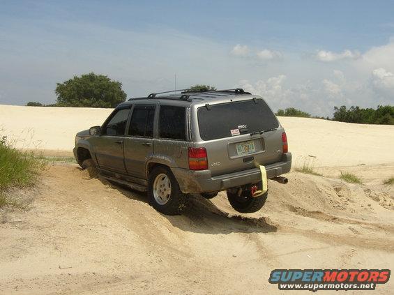 Jeep Grand Cherokee stuck in sand dune, rear wheel off the ground