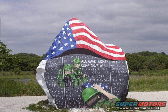War memorial stone with American flag and painted soldiers, listing names