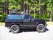 1994 Ford Bronco - This black Ford Bronco is equipped with a roof rack, spare tire, and shovel, ready for adventure.