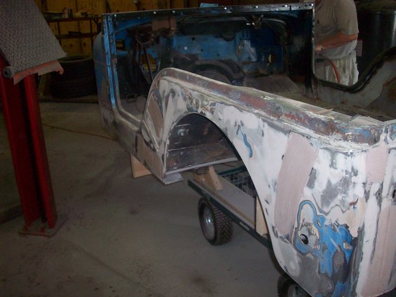 Blue Jeep body on dolly, undergoing bodywork