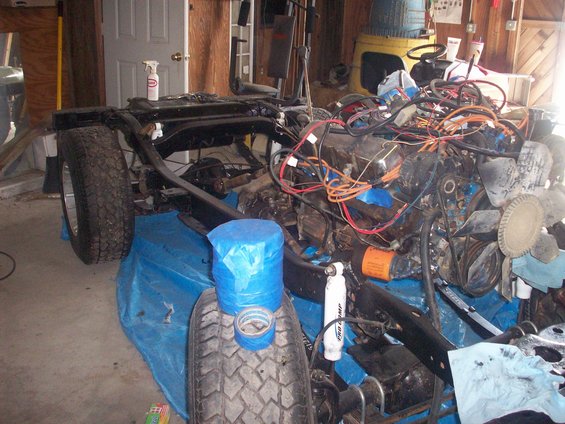 Vehicle frame with engine, transmission, and wiring harness disassembled in a garage