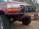 1989 Ford Bronco - This red Ford Bronco features a custom front bumper with auxiliary lights and off-road tires.