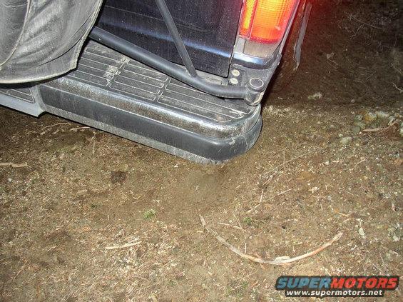 Rear bumper and spare tire on a dark SUV parked on dirt