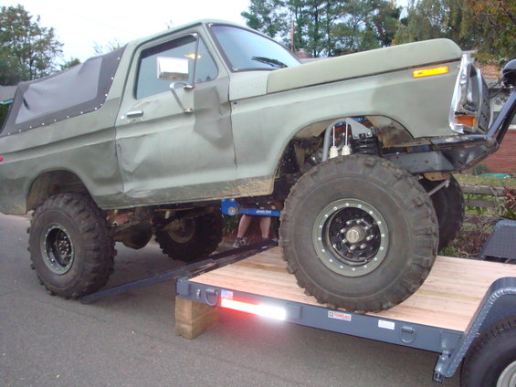 Olive green lifted truck with soft top on trailer ramp