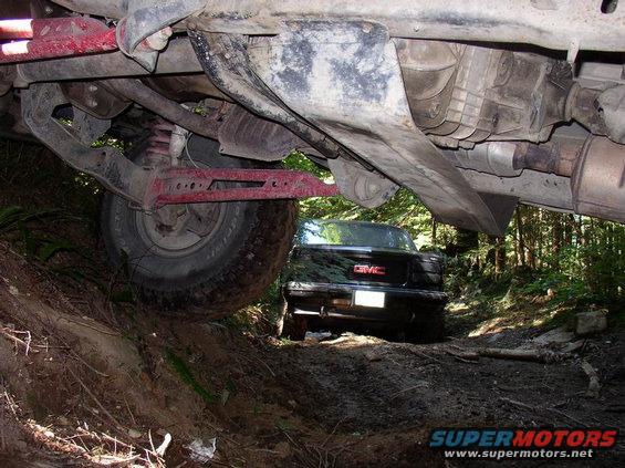 Rear view of black GMC pickup truck on dirt road, seen from underneath another vehicle