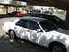2001 Ford Crown Victoria - Side view of a white 2001 Ford Crown Victoria parked under a carport with other vehicles present.