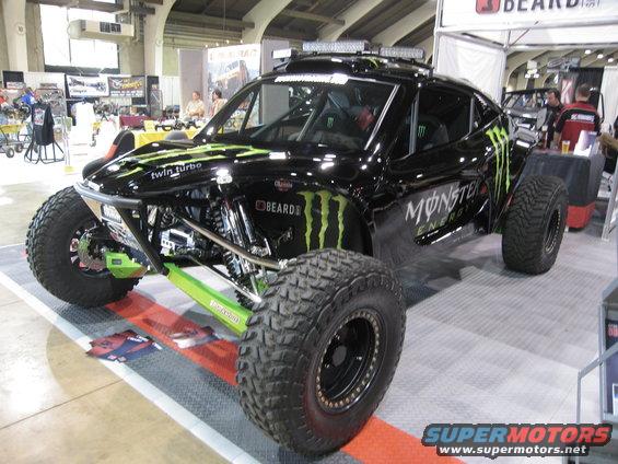 Black Monster Energy trophy truck with green accents and large off-road tires
