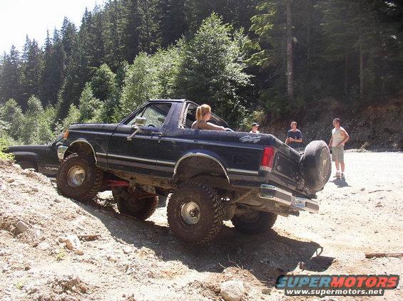 Dark blue 1987 Ford Bronco off-roading, rear view with spare tire