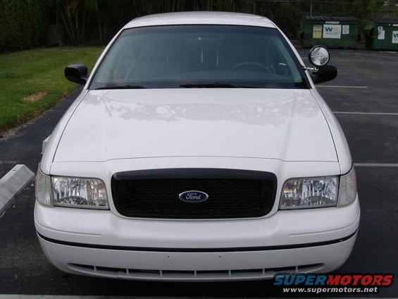 Front view of a white Ford Crown Victoria police car. Black grille with Ford logo