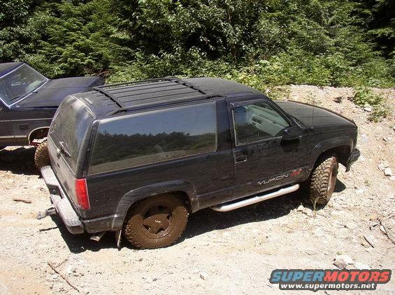 Black 1995 GMC Yukon GT with muddy tires, parked next to another vehicle